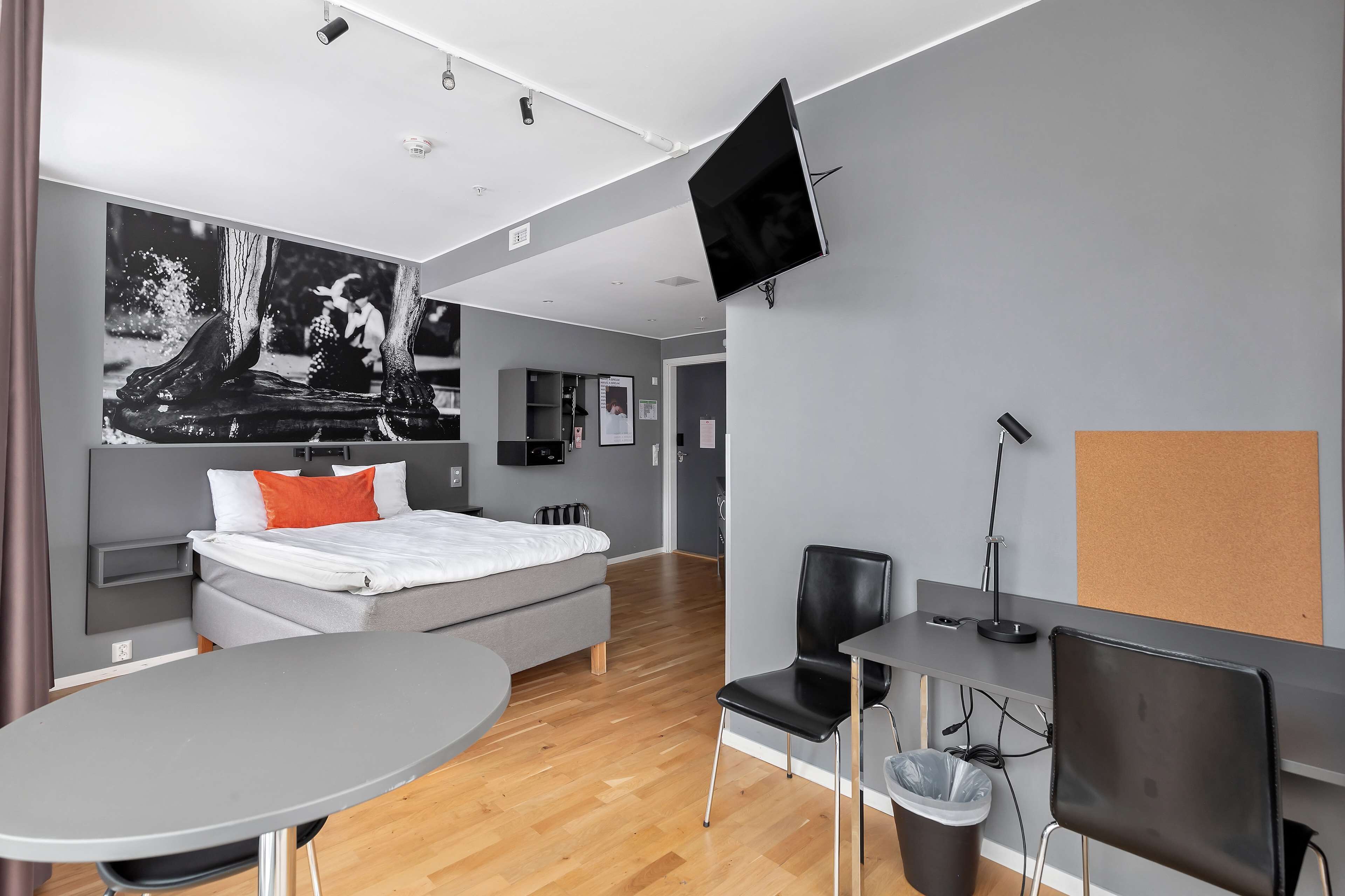 Een moderne hotelkamer met een bed, een bureau, een stoel, een televisie en een schilderij aan de muur.