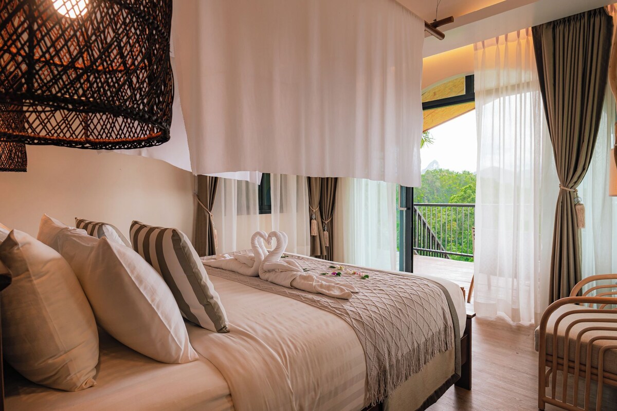 Una cama con almohadas, un dosel y vistas al follaje exterior.