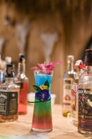 A bar setting with a colorful cocktail and various liquor bottles.