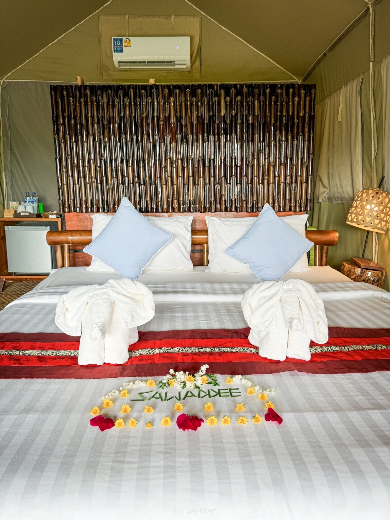 A bed with two pillows, a red and white bedspread, and a floral arrangement.