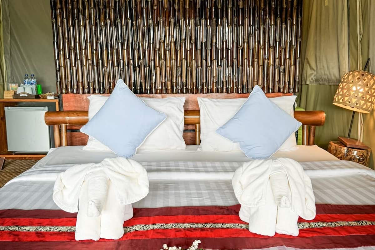 A bed with two pillows, a red and white bedspread, and a floral arrangement.