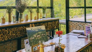 Mostrador de recepción con vistas a exuberante follaje, techo de bambú y decoración rústica.