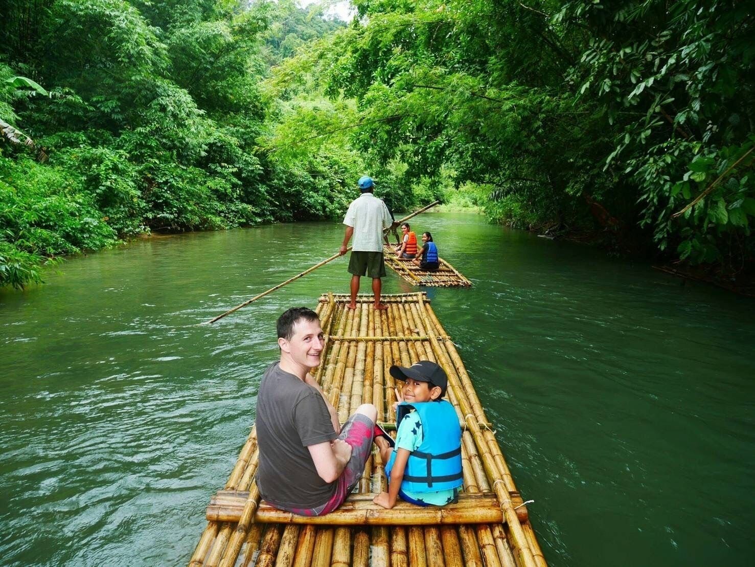 Ein Bambusfloß auf einem Fluss, umgeben von dichtem Grün.