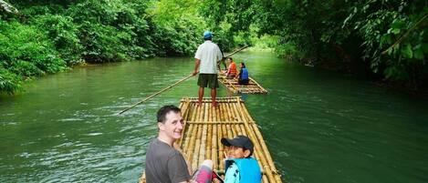 Ein Bambusfloß auf einem Fluss, umgeben von dichtem Grün.