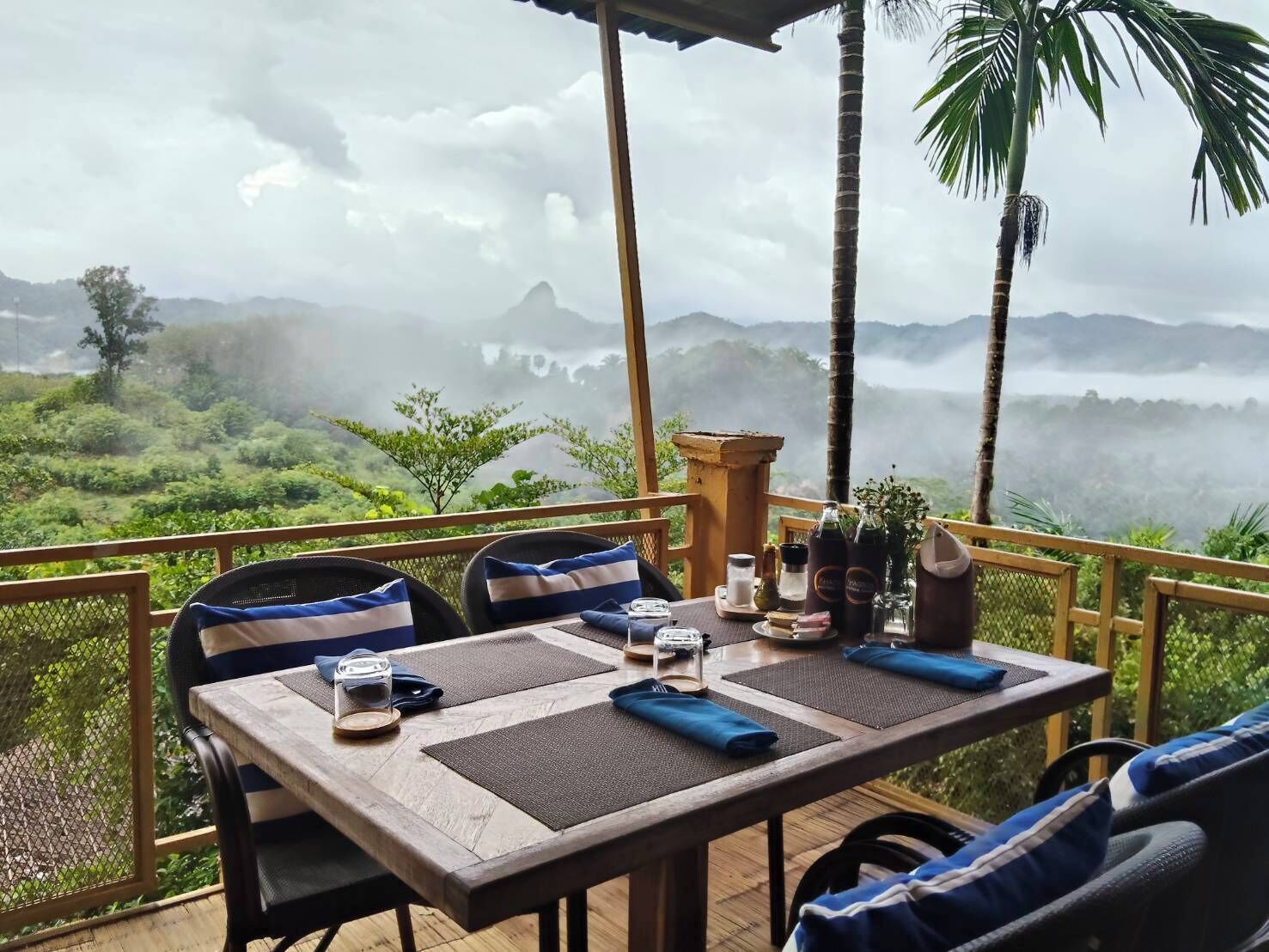 Mesa de comedor al aire libre con vistas a montañas cubiertas de niebla.