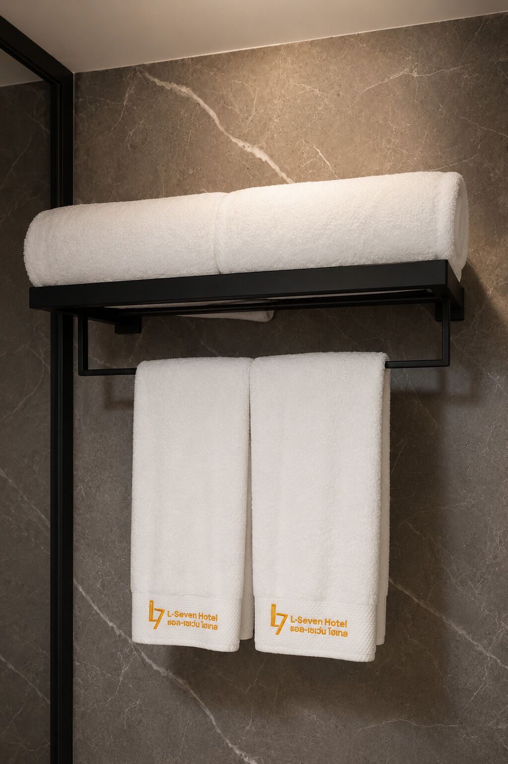 A towel rack with two white towels and a folded towel.