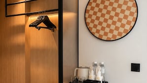 A modern hotel room with a built-in wardrobe, a round mirror, a bench, and a small table with toiletries. - L-Seven Hotel (Bangkok)