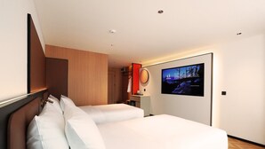 Habitación de hotel con cama, escritorio, televisor y pared de paneles de madera.
