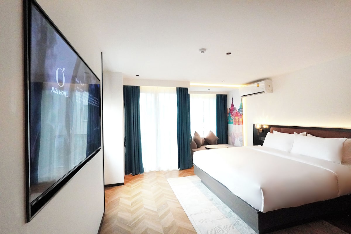 Habitación de hotel con una cama grande, un televisor montado en la pared y vista a un edificio.