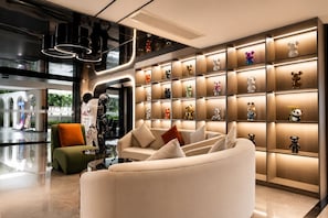 Eine moderne Lobby mit einer Couch, einem Glastisch und einer Wand voller Bärenfiguren.