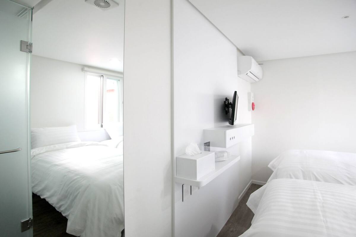 Una habitación de hotel moderna con una cama, un televisor y un estante con artículos de aseo.