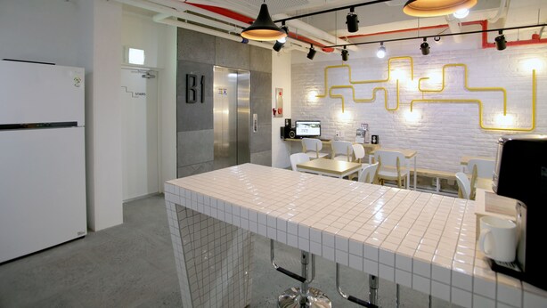 A modern kitchen with a tiled countertop, stainless steel appliances, and a seating area with chairs and tables.