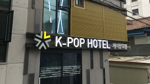 A K-pop hotel with a modern facade, large windows, and a prominent sign.