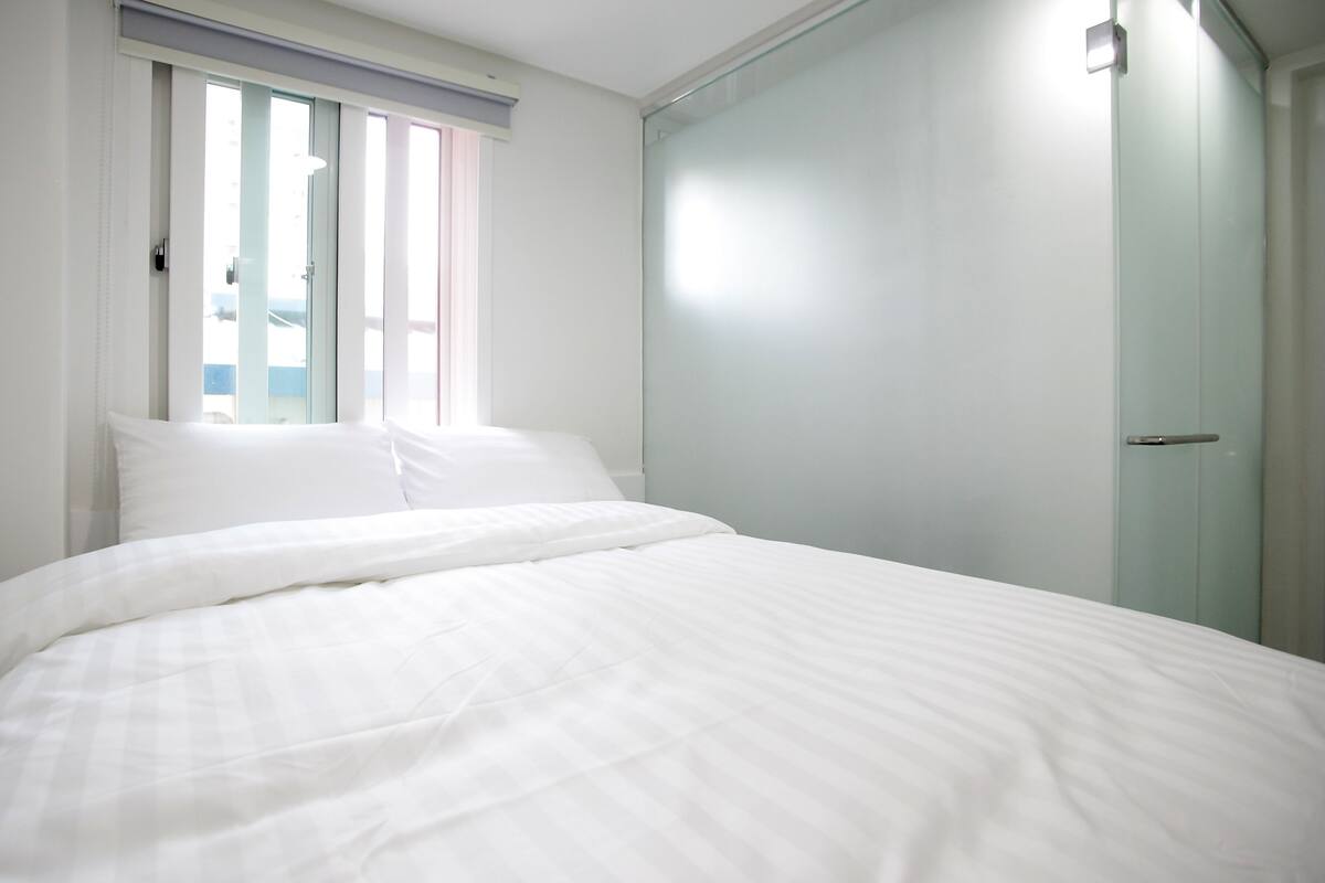 Un dormitorio con cama, ventana y puerta.