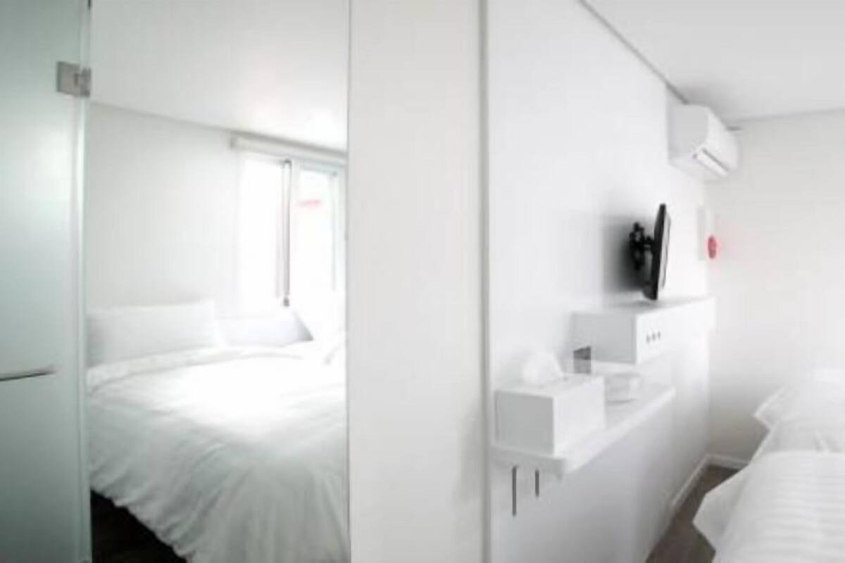 Una habitación de hotel con una cama, una mesita de noche, un televisor y una ventana.