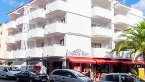 Ein mehrstöckiges Gebäude mit Balkonen, einer Snackbar und einem Café.