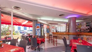 Ein Restaurant mit Tischen, die rot gedeckt sind, einer Pepsi-Fountain und einer Bar mit Hockstühlen.