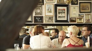 A restaurant with patrons seated at tables, framed pictures on the wall, and a menu board visible. - Limes Hotel (Wehrheim)