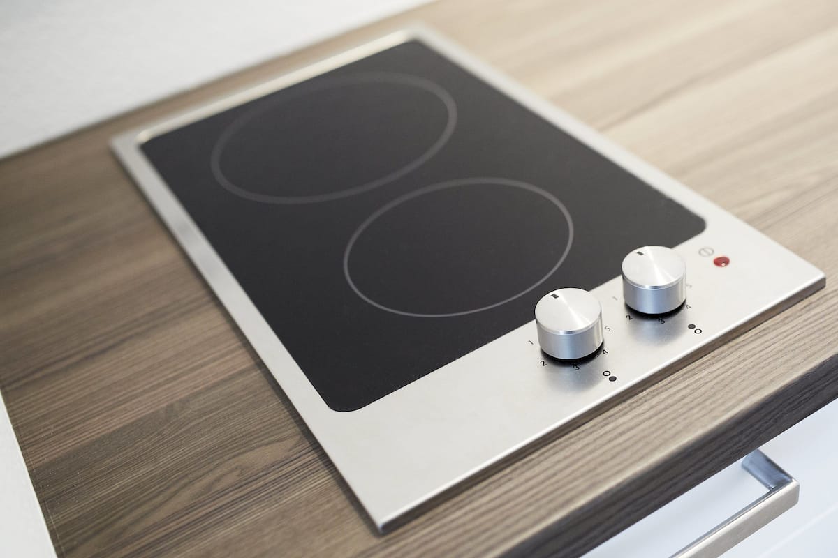 A modern kitchen with a built-in induction cooktop and a stainless steel range hood.