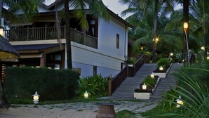 A resort with a staircase leading to a balcony, surrounded by palm trees and well-lit pathways. - Tropicana Resort (Phu Quoc)