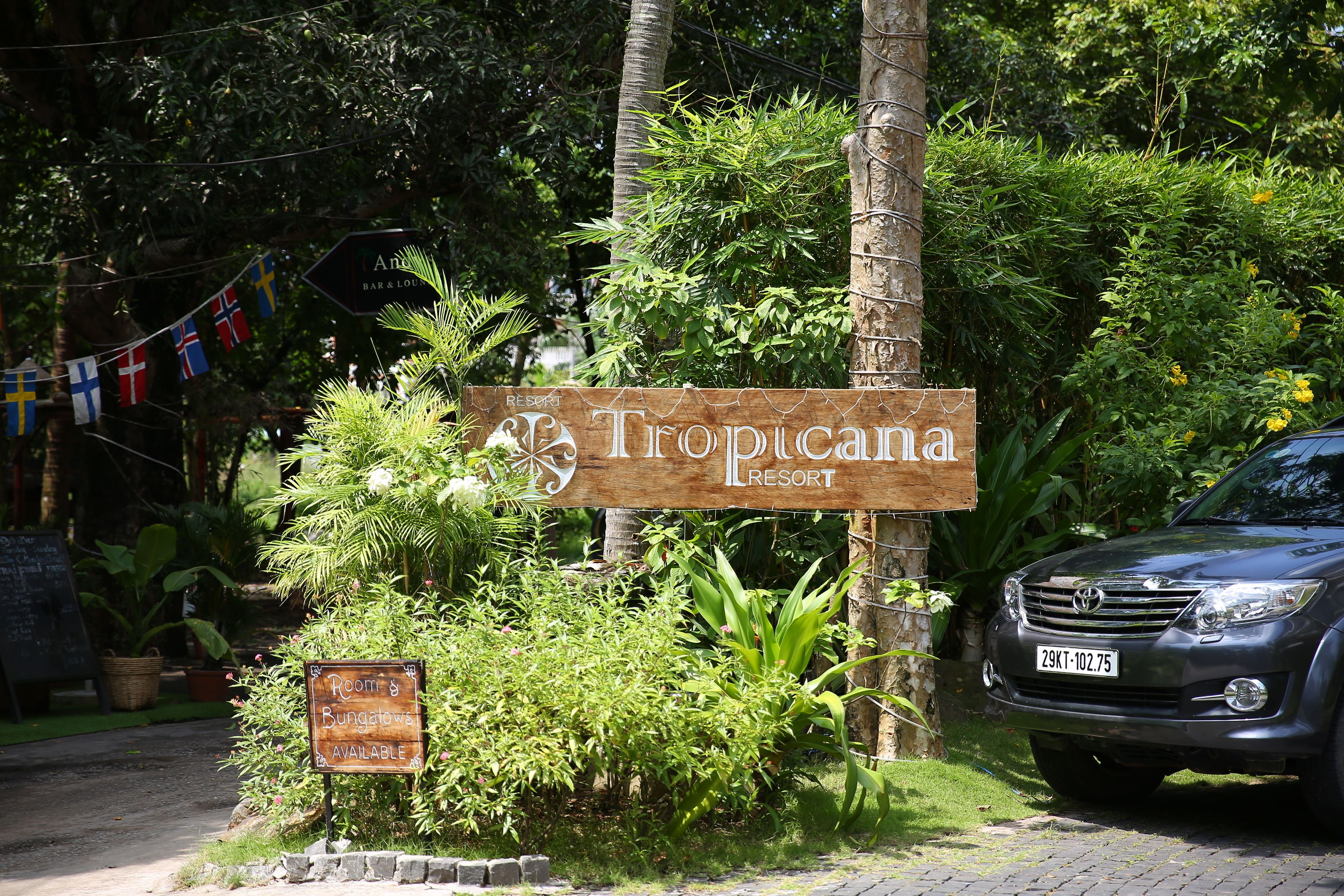 Une enseigne indiquant le Tropicana Resort, avec une autre enseigne précisant que des chambres et des bungalows sont disponibles.