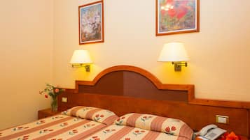 Ein Hotelzimmer mit einem hölzernen Kopfteil, zwei Nachttischlampen, einem Telefon und floralen Wandbildern.
