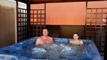 Un jacuzzi con dos personas adentro, rodeado de paneles de madera y un piso de baldosas.