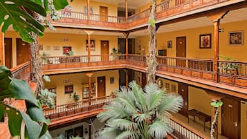 A multi-level atrium with wooden balconies, large green plants, and a high ceiling with skylights.