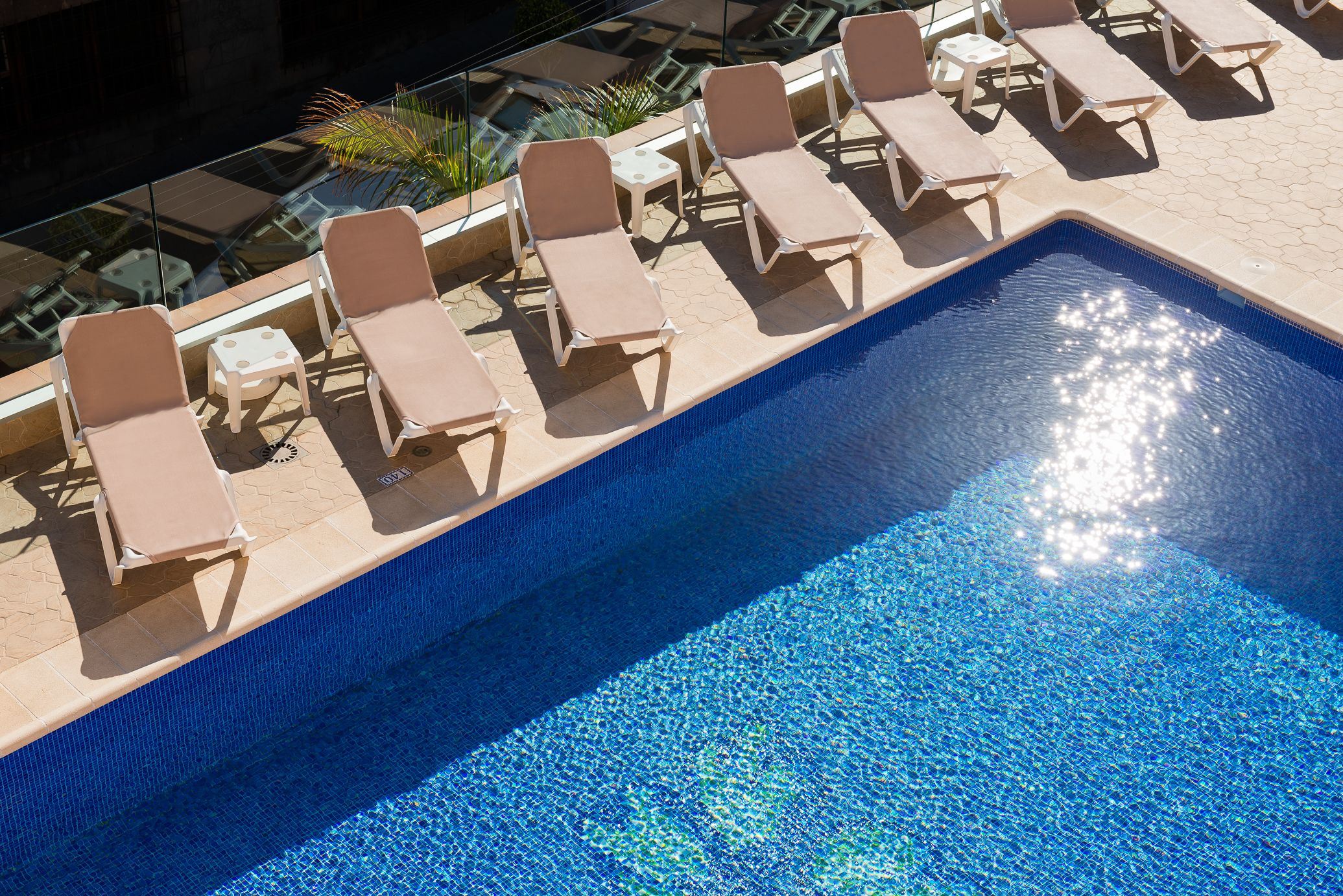 A swimming pool with lounge chairs and a small table.