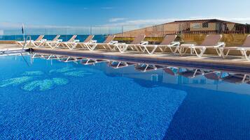 Ein Pool mit Liegestühlen und Blick auf den Ozean.