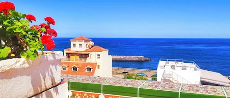 Un edificio costero con techo de tejas, vistas al mar y una pared decorativa con motivos florales.
