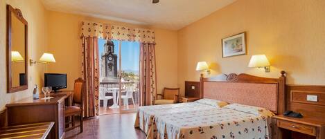 A hotel room with a bed, a desk, a chair, a television, and a view of a clock tower through the window.