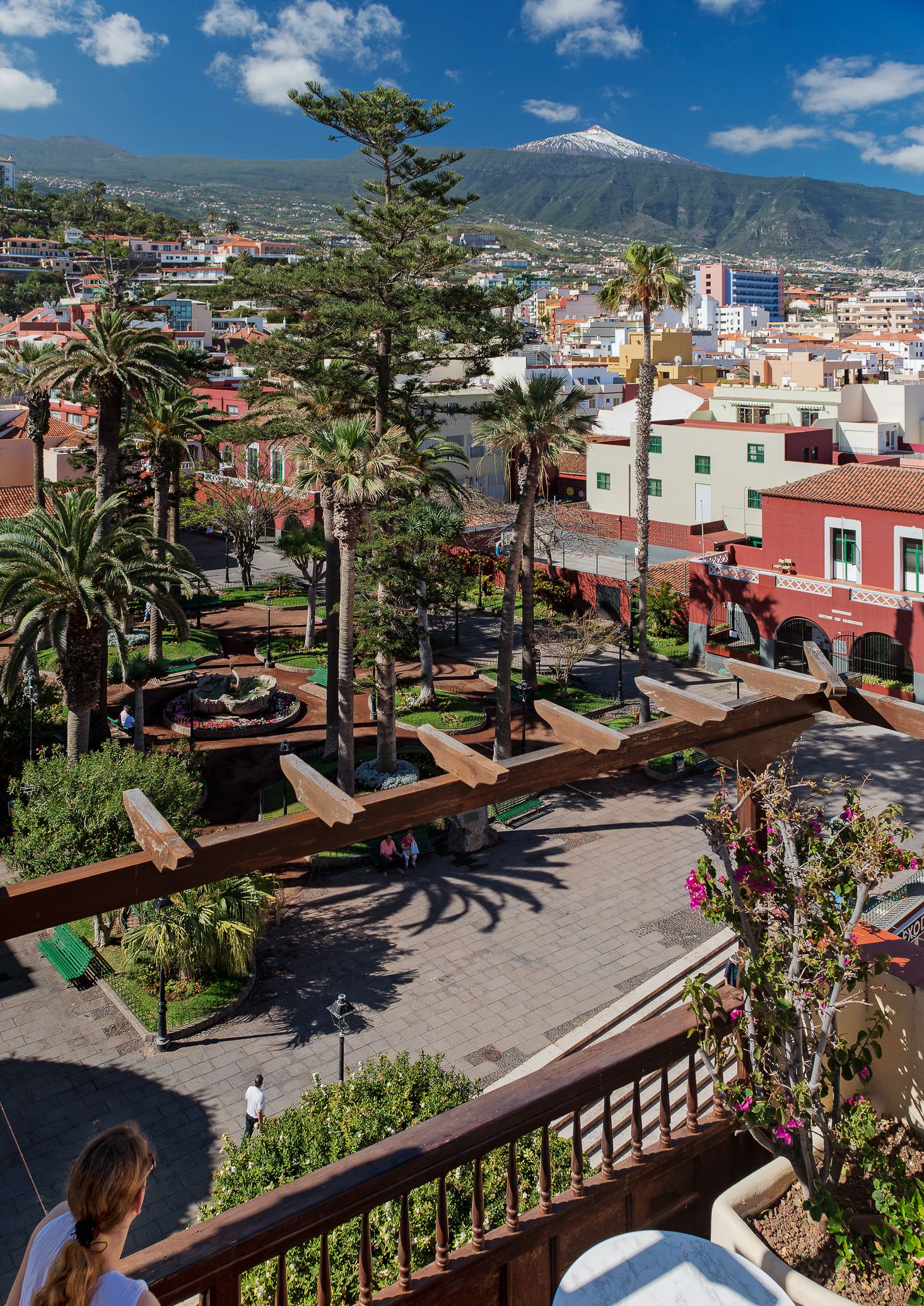 A courtyard with palm trees, a fountain, and a view of a mountain.