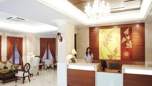 Um hall de hotel com balcão de recepção, área de estar e um candelabro.