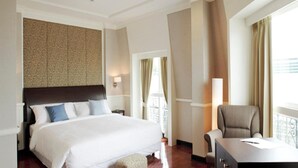 Quarto de hotel com uma cama grande, uma escrivaninha e vista para o exterior.