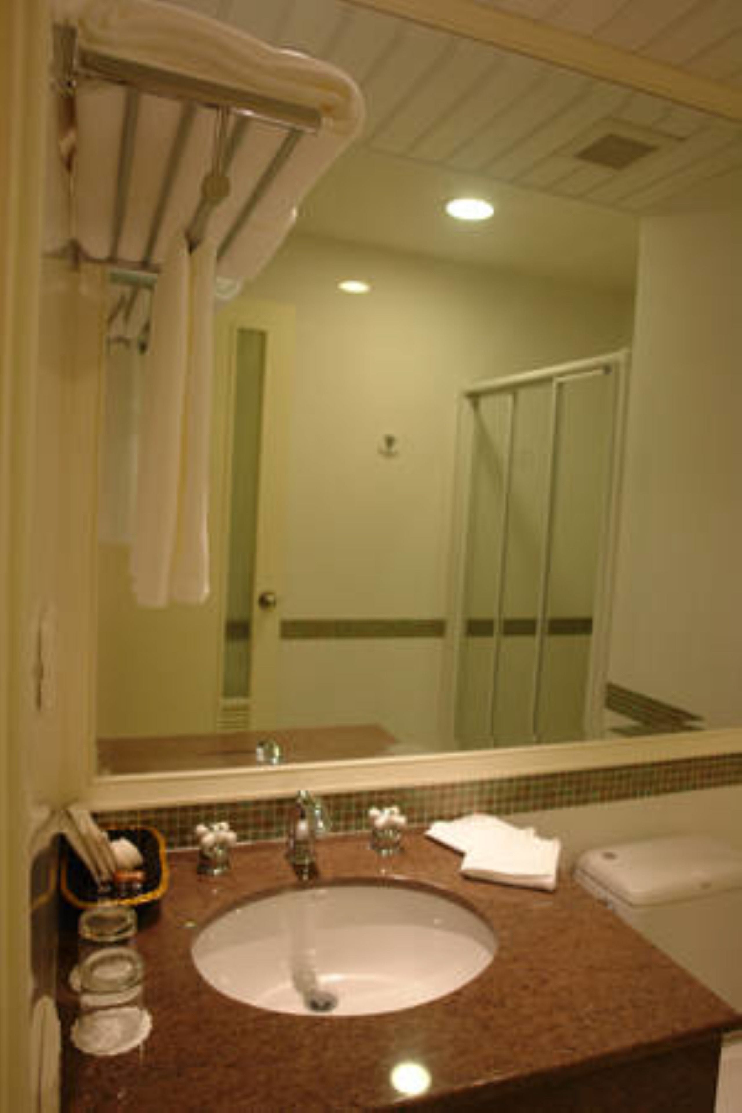 Un baño con lavabo, espejo y ducha.