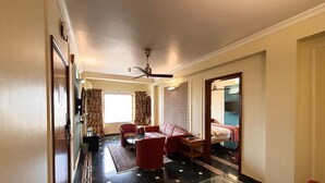 A hotel room with a sofa, armchair, and a small table. - Hiltop Hotel (Mumbai)