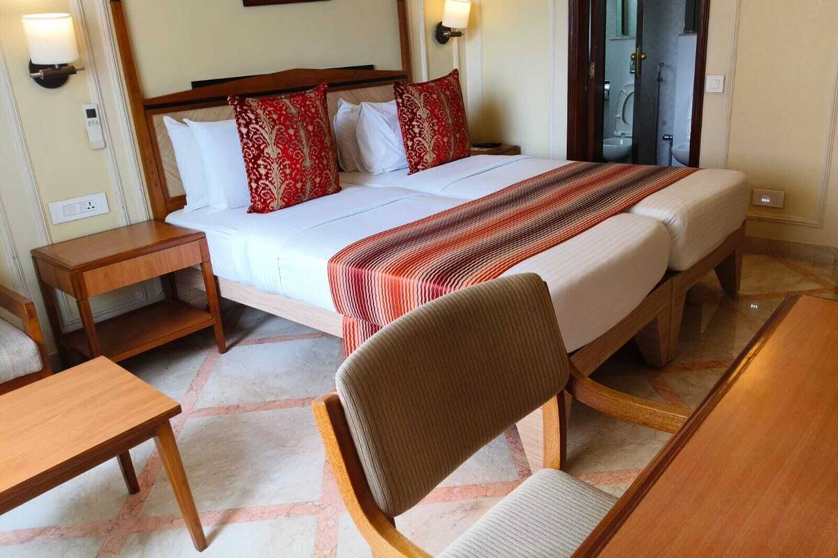 A hotel room with a double bed, two bedside tables, a chair, and a view of the outside.