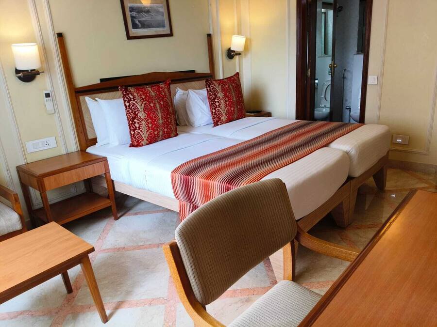 Camera d'albergo con un letto matrimoniale, due comodini, una sedia e vista sull'esterno.