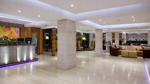 A spacious lobby with a reception desk, seating area, and a large pillar. - Hiltop Hotel (Mumbai)