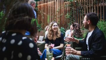 A group of people sitting on wicker chairs outdoors, engaged in conversation.