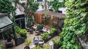 An outdoor patio area with seating, planters, and a wooden pergola. - The Circus Hotel (Berlin)