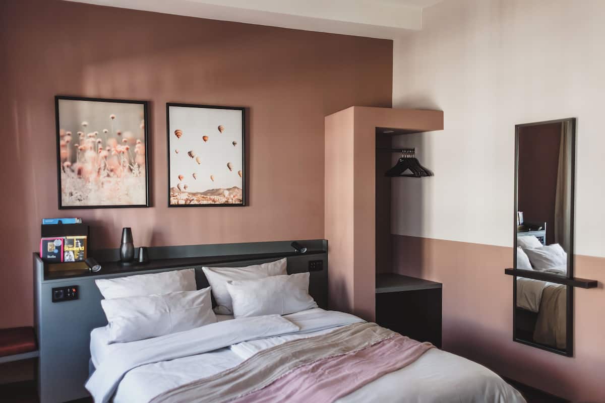 Ein Hotelzimmer mit Bett, Nachttischen, einem Spiegel und Bildern an der Wand.