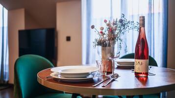 Una mesa de comedor con platos, cubiertos, una botella de vino y un florero con flores.