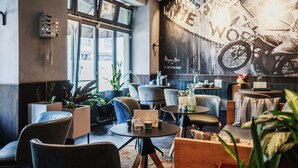 A modern interior with seating, a large wall mural, and potted plants. - The Circus Hotel (Berlin)