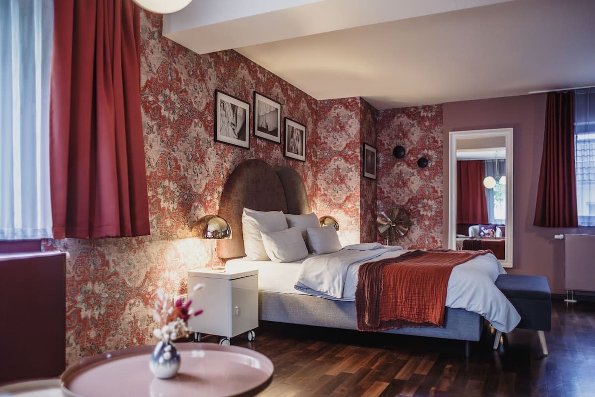 Ein Schlafzimmer mit Bett, Nachttisch, Lampe und Spiegel.