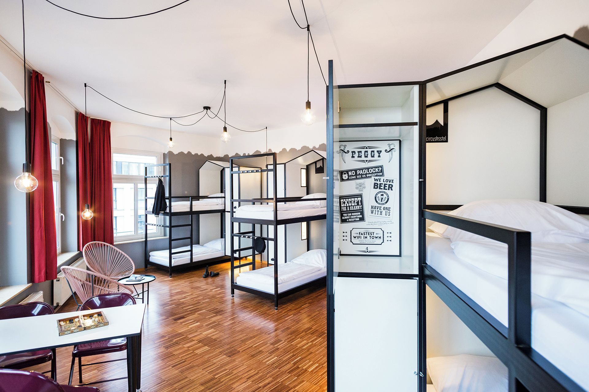 A dormitory-style room with bunk beds, a dining area with chairs, and a table with a tray.