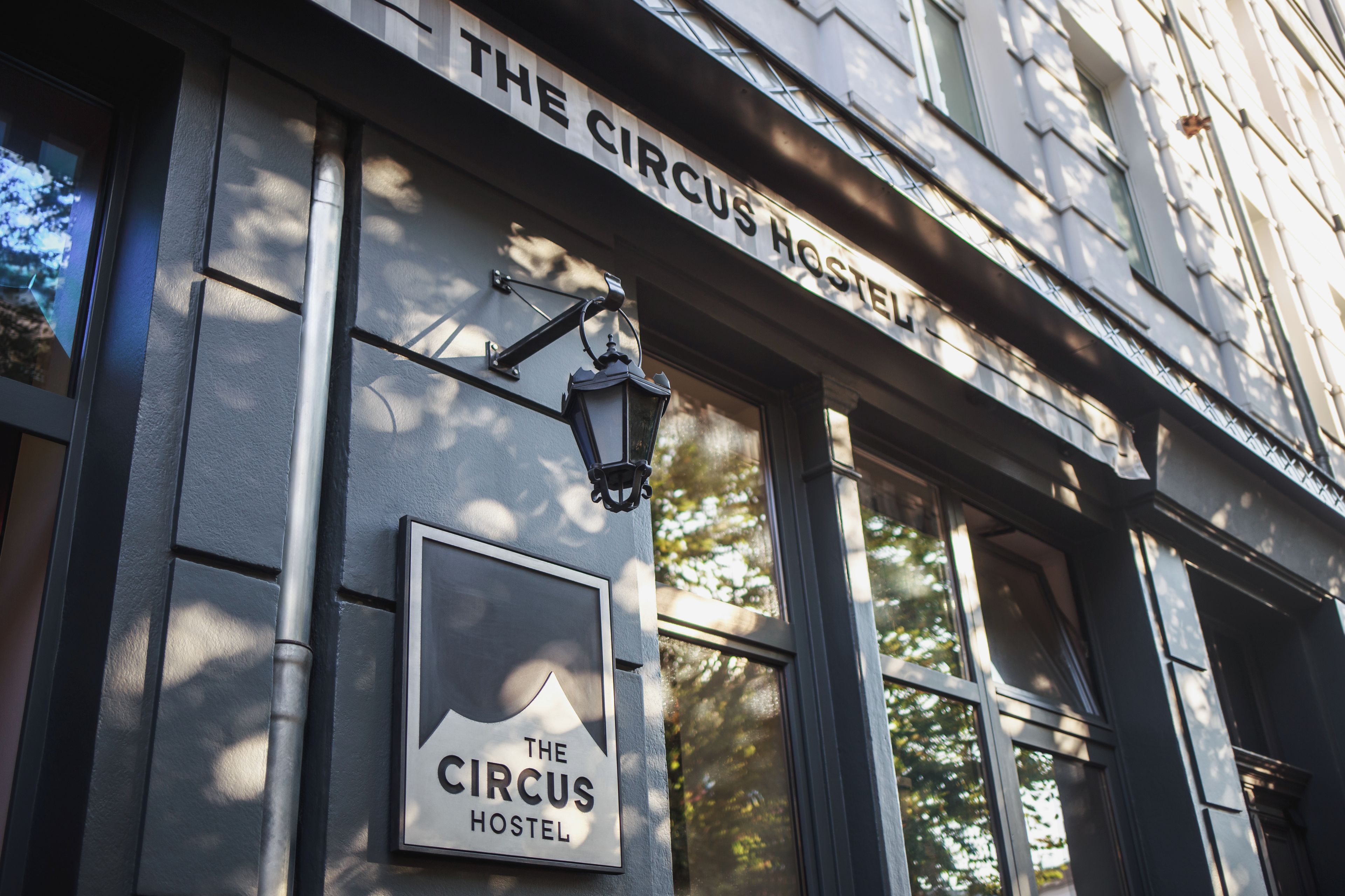 Une enseigne indiquant « The Circus Hostel », fixée à un bâtiment doté de grandes fenêtres.