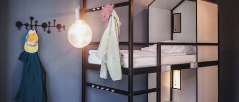 A bunk bed room with a hanging light fixture, a towel, and a jacket on the wall.