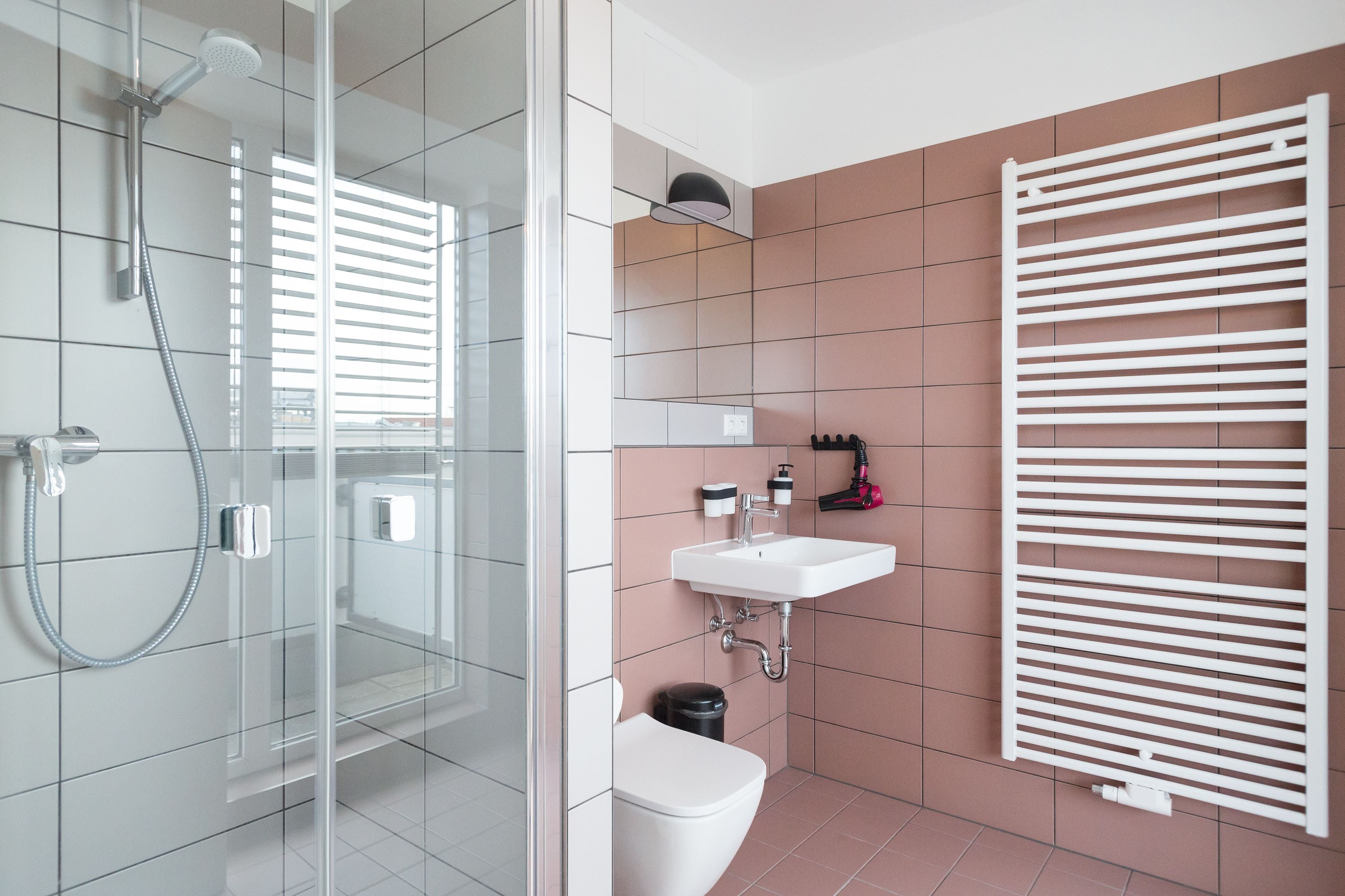 Ein Badezimmer mit einer Glaskabine zur Dusche, einem weißen Waschbecken und einem Handtuchhalter.